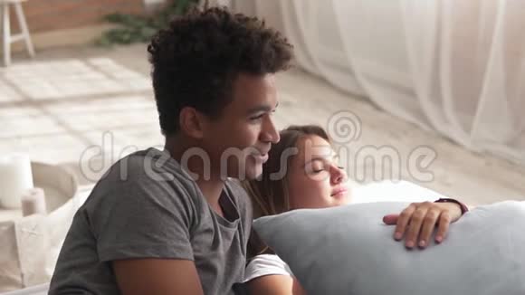 年轻可爱的多民族夫妇躺在床上聊天英俊的非洲男人在说些什么可爱的男人和女人视频的预览图