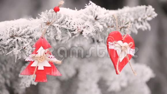 红色木制圣诞玩具心和杉树挂在雪地圣诞树的树枝上视频高清视频的预览图