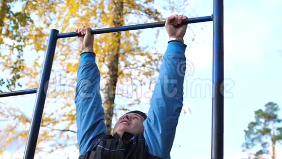 在新鲜空气中锻炼年轻强壮的家伙在酒吧里做运动秋季公园视频的预览图