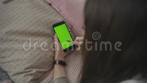 绿色屏幕用带有色度键的手机拍摄长黑发的年轻白种人女性的肩部镜头视频的预览图