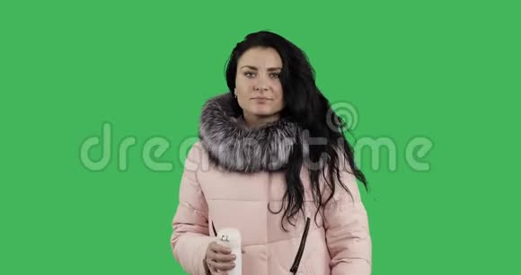 一个穿着冬衣的年轻女人去喝热杯里的茶视频的预览图