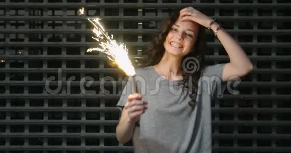 金属栅栏前手中拿着火花的女孩的慢镜头视频的预览图