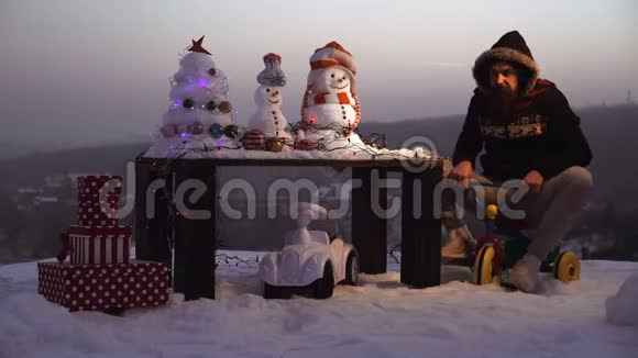 惊讶的人骑三轮车在雪景上冬日里的雪人和圣诞树圣诞节和新年的乐趣视频的预览图
