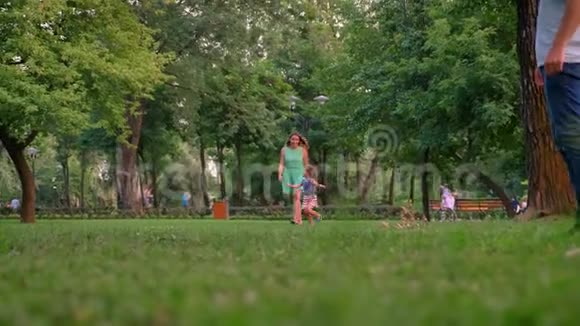 一家人夏天在公园散步女儿在和父母玩耍在草地上奔跑视频的预览图
