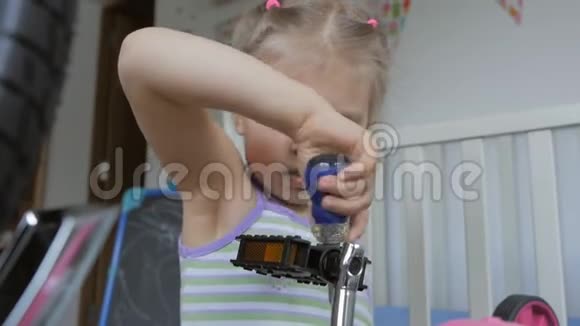 一个小女孩用螺丝刀坐在托儿所里自修自行车视频的预览图