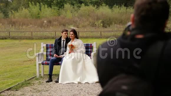 新婚夫妇在长凳上向摄影师摆姿势视频的预览图