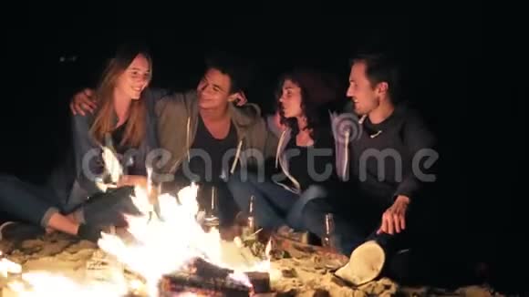 不同的人群在深夜坐在炉火旁互相拥抱烹饪香肠和视频的预览图