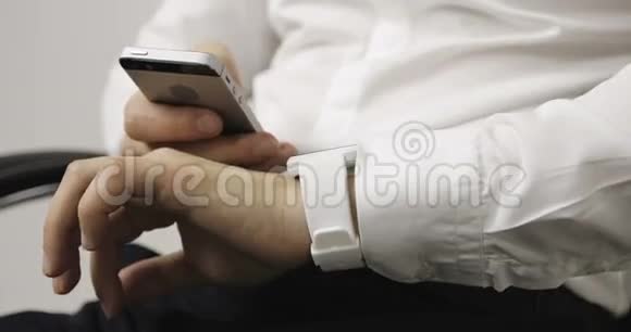 穿着白色衬衫的贴身商人在可穿戴的智能手表电脑设备上做手势视频的预览图