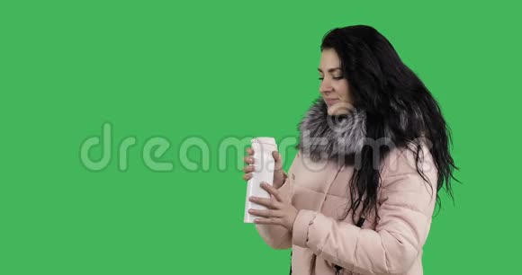 穿着冬衣的年轻女模特从白色热杯中喝茶视频的预览图