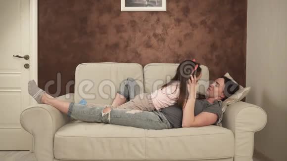快乐的母亲和小女儿躺在沙发上拥抱视频的预览图