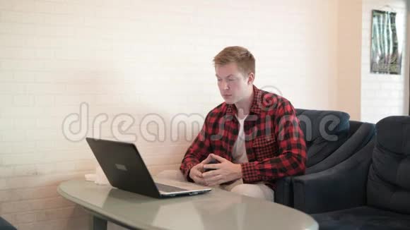 年轻英俊的时髦男人一边喝咖啡一边用手机和笔记本电脑视频的预览图