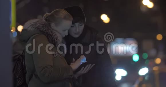 在街上等公共汽车时使用平板电脑的女性朋友视频的预览图