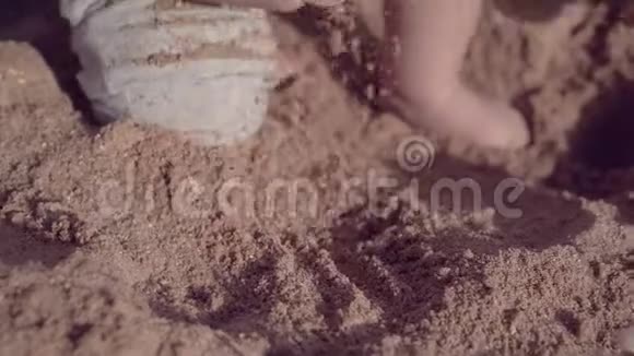 小宝宝在沙滩上玩沙子手和腿的特写镜头视频的预览图