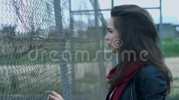 一位年轻的女士她长着一头美丽的长发抚摸着栅栏的网视频的预览图