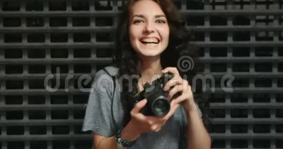 幸福少女用老式电影摄影机在金属网格围栏前拍照视频的预览图