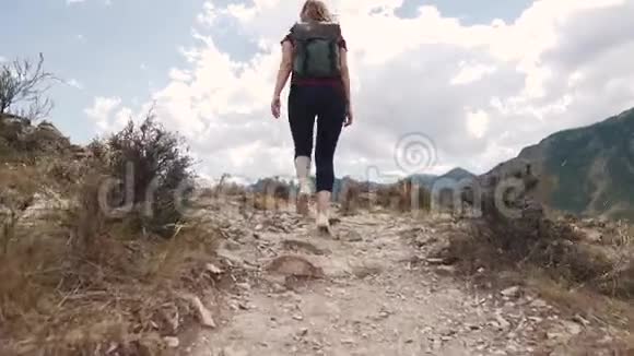 女孩走在岩石地形的小径上带背包的年轻女游客视频的预览图