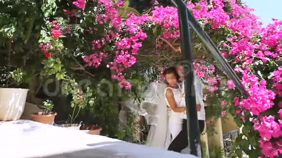 在鲜花的背景下快乐的新娘和新郎结婚纪念日视频的预览图