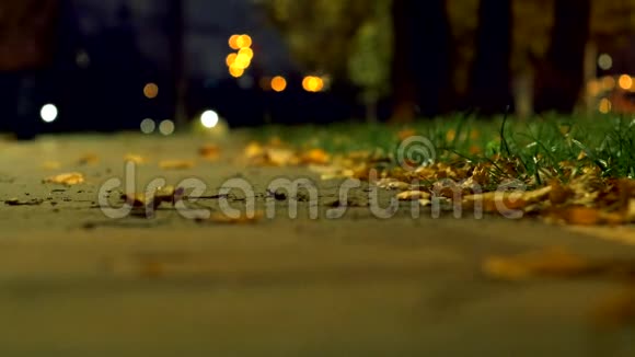公园在秋天黑暗的夜晚一个人走在人行道上从模糊的背景中查看太阳神镜头视频的预览图