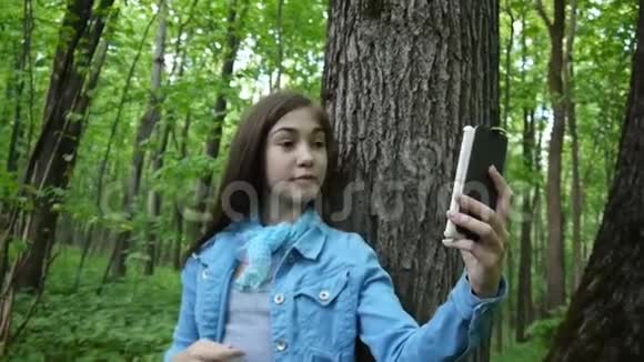 女孩在公园夏天拍自拍照片智能手机噗嗤笑了录像片段视频的预览图