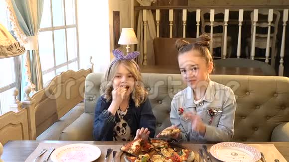 漂亮的小女孩在外面吃饭女孩们在披萨店笑着吃披萨享受全高清视频的预览图