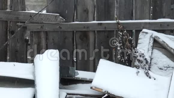 村子里下雪了许多雪花飘落下来旧的木栅栏落在后面视频的预览图