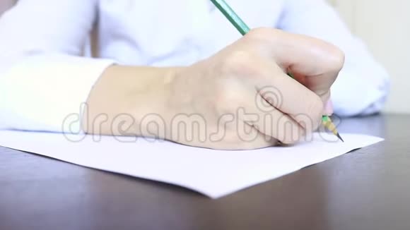女人穿着休闲服坐在桌子旁用铅笔在一张纸上写字视频的预览图