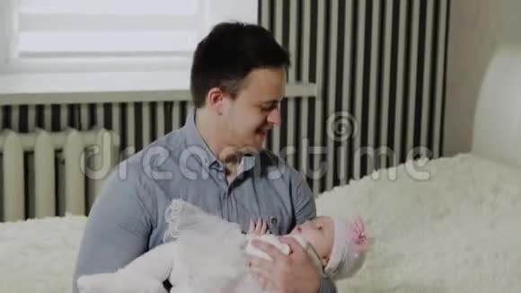 年轻的爸爸把一个小女孩抱在床上视频的预览图