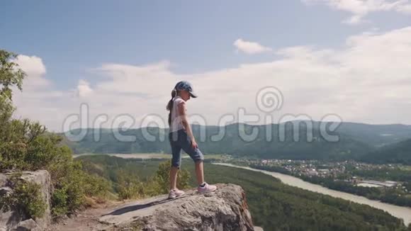儿童旅行者的肖像站在岩石上悬崖上的小女孩视频的预览图