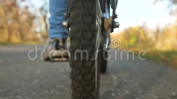 推脚踏车的女孩的腿带踏面的轮子特写在柏油路上骑自行车视频的预览图