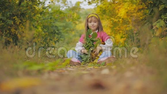 美丽的长发小女孩把叶子向上扔笑秋天在城市公园视频的预览图