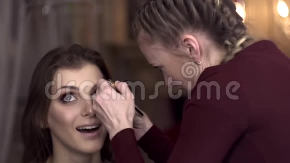 化妆师在美容院给一个漂亮女孩画睫毛视频的预览图
