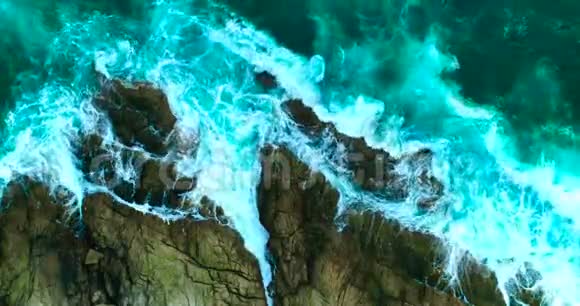 空中美丽的海浪岩石海岸线上有白色的泡沫视频的预览图