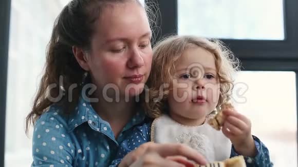 坐在妈妈腿上吃甜蛋糕的小女孩视频的预览图