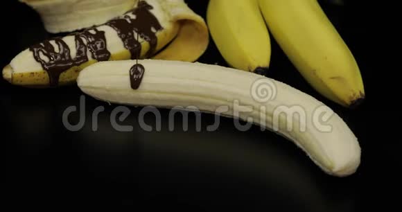 用融化的黑巧克力糖浆浇香蕉黑色背景视频的预览图