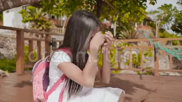 一个背着背包的菲律宾女学生坐在热带海岸附近哭泣悲伤的心情视频的预览图