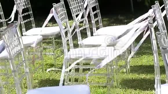 白色和粉红色的丝带在椅子上飘扬结婚典礼透明椅子视频的预览图