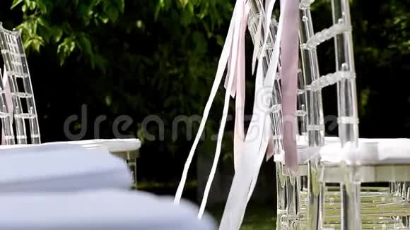 白色和粉红色的丝带在椅子上飘扬结婚典礼透明椅子视频的预览图