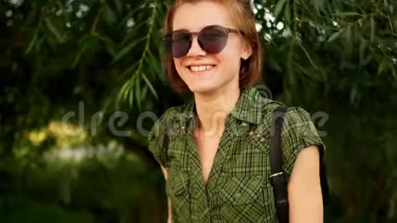 动态视频一幅红发女孩戴太阳镜的特写肖像背景是夏季绿色自然视频的预览图