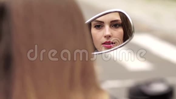 女孩把嘴唇涂在摩托车镜子里视频的预览图