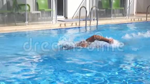 强壮的男人在游泳池里游泳阳光明媚的一天年轻人漂过旅馆的盆地暑假或视频的预览图