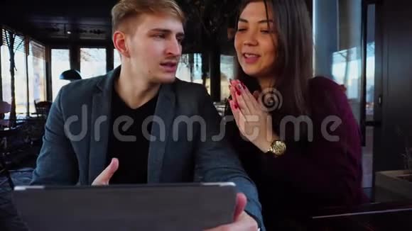 一对夫妇坐在咖啡馆里用银笔记本设计新房子视频的预览图