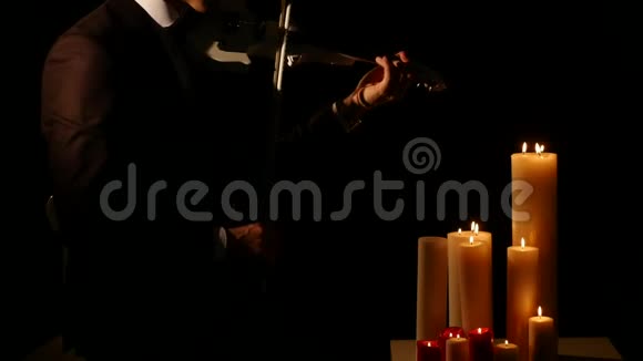 关闭小提琴演奏者在黑色背景下用蜡烛演奏乐器视频的预览图