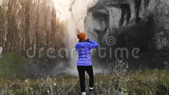 一个女孩是一个专业的风景摄影师站在河边的石头上拍摄一部大型史诗视频的预览图