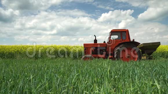 拖拉机和农民在农业小麦和油菜田和戏剧性的云视频的预览图