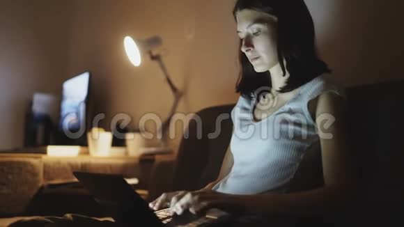 年轻有魅力的女性晚上在家里使用笔记本电脑分享社交媒体视频的预览图