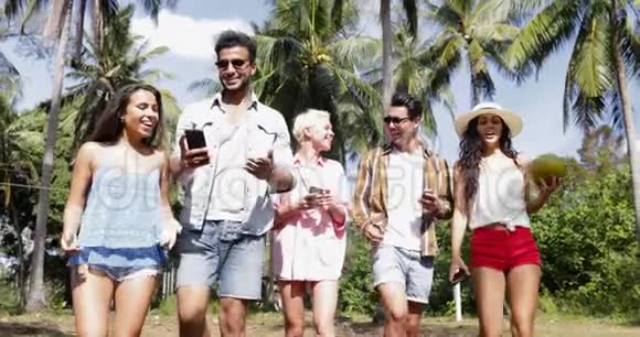群聊使用手机智能手机在棕榈树下漫步户外快乐微笑混合种族男女视频的预览图