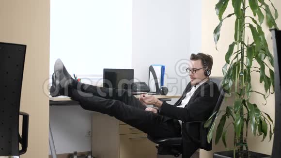 年轻人坐在办公室用耳机说话挤压手扩张器60英尺视频的预览图
