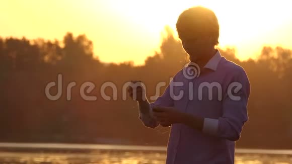 年轻人听他的手机在湖边跳舞视频的预览图