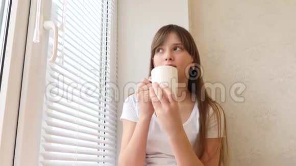 漂亮的女孩带着一杯热茶坐在窗台上微笑着视频的预览图
