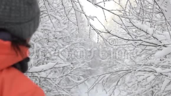 女人走在一片美妙的冬日森林里脖子上触摸着树枝雪花飘落视频的预览图